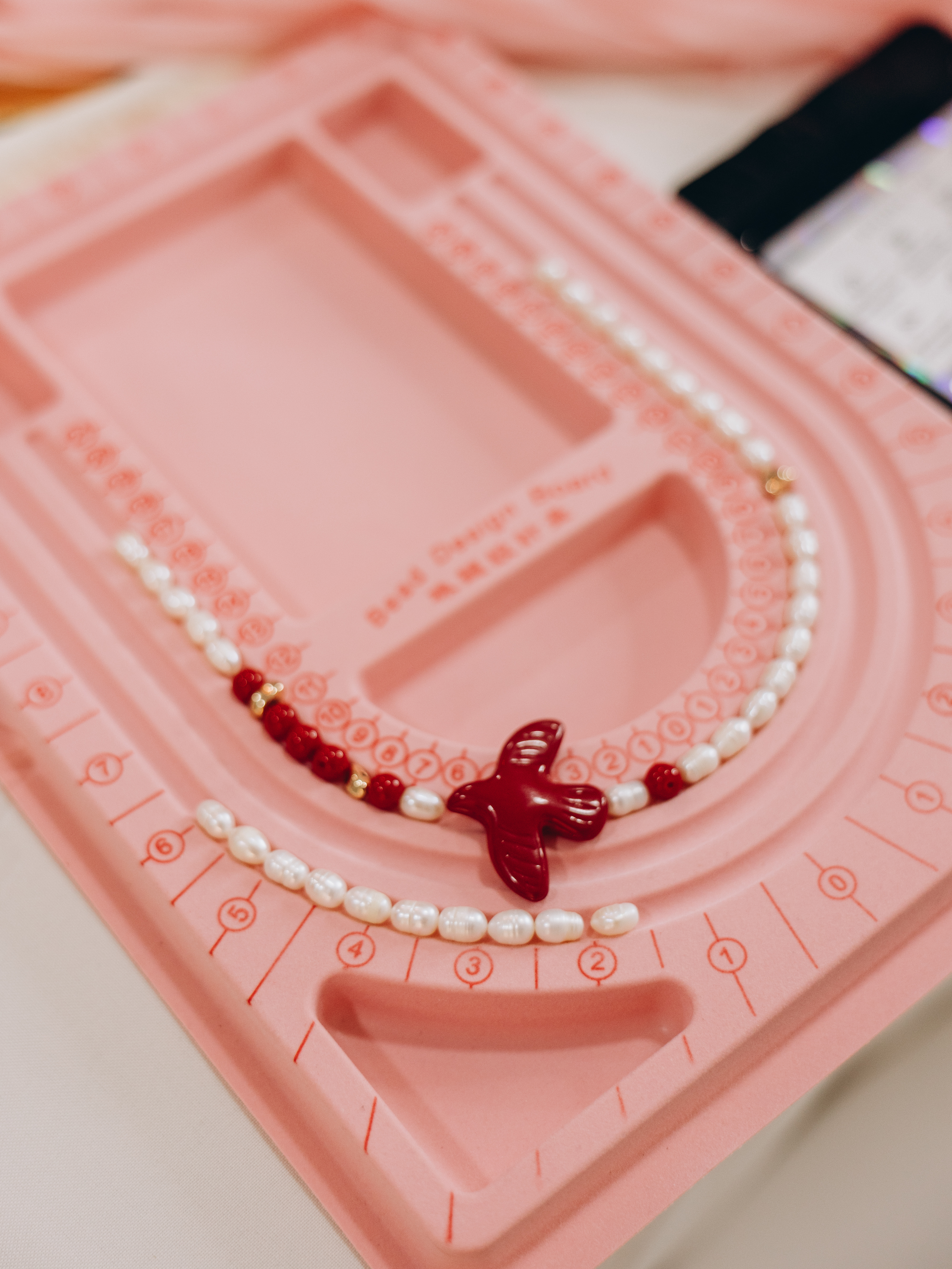 Handcrafted pearl and natural stone necklace arranged on a jewelry design board