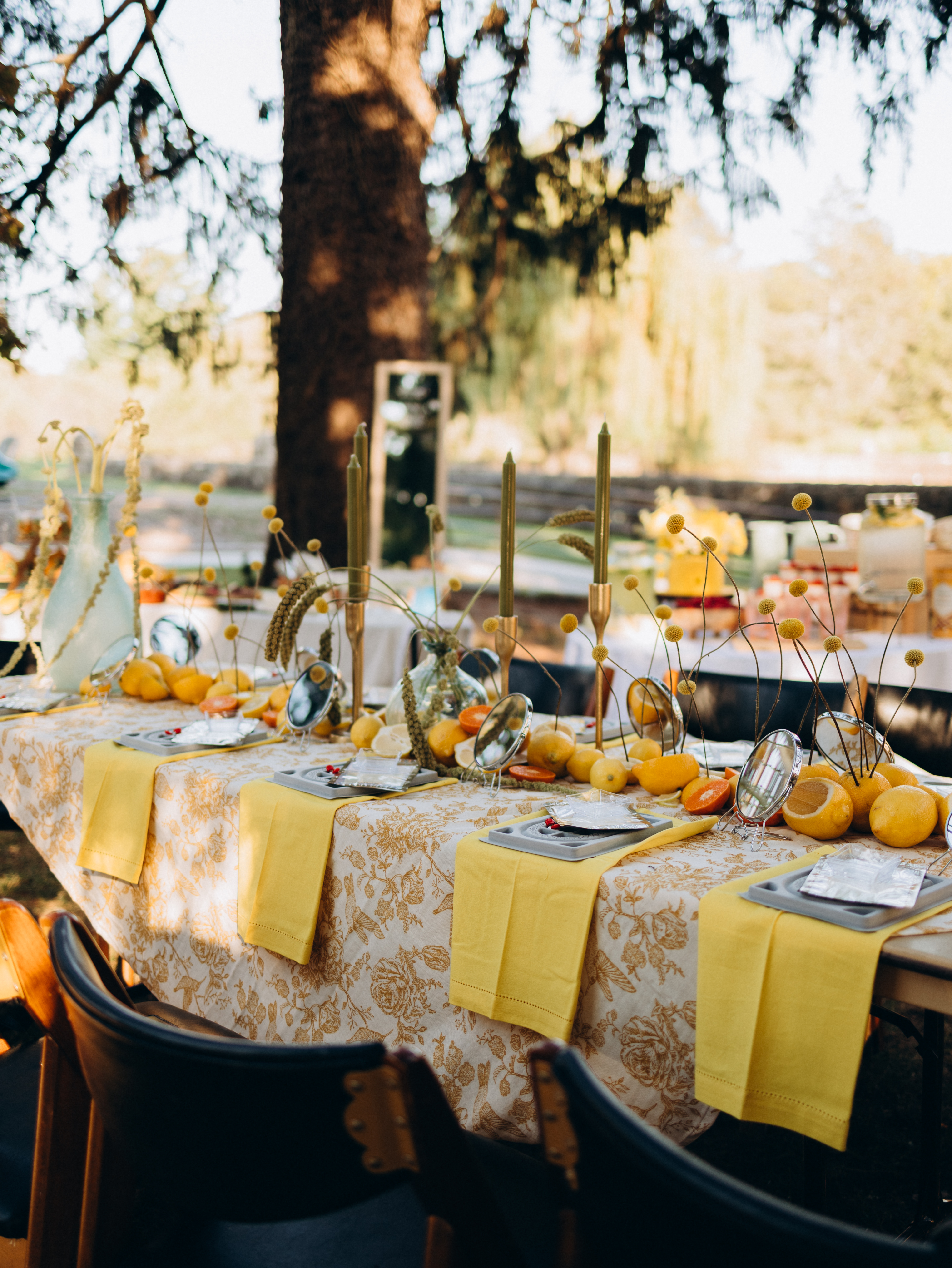 A jewelry-making workshop table set with materials, mirrors, flowers and citrus